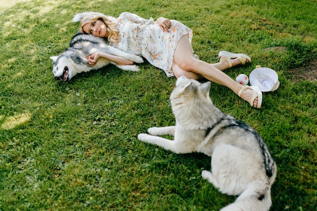 Eine junge romantische Frau, die mit Hunden auf dem Gras liegt