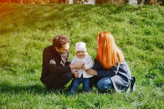 Eine junge rothaarige Mutter spielt im Park mit ihrem Ehemann und ihrer kleinen Tochter