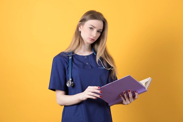 Eine junge Ärztin im OP-Anzug mit einem Buch