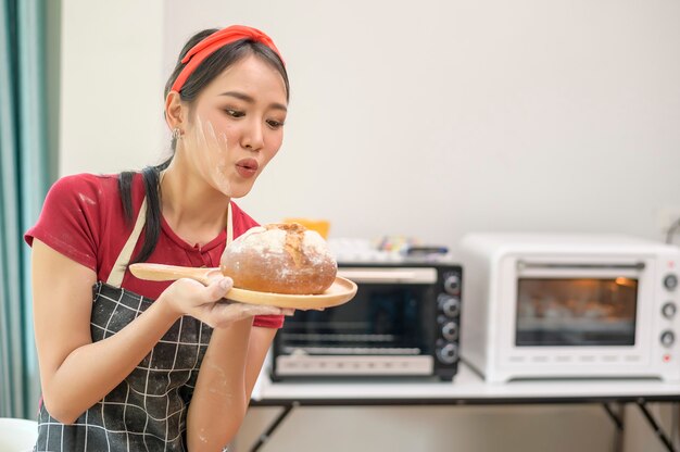 Eine junge schöne Asiatin backt in ihrem Küchen-, Bäckerei- und Café-Geschäft