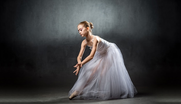 Eine junge schöne Ballerina posiert im Studio. Eine kleine Tänzerin. Ballett.