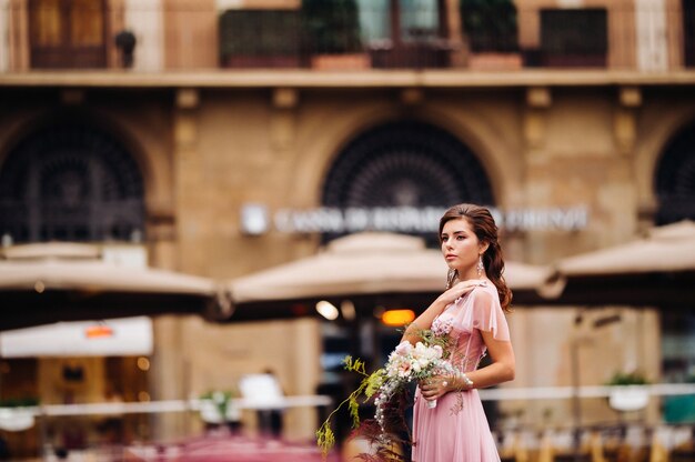 Eine junge schöne Braut steht im Zentrum der Altstadt von Florenz in Italien. Braut in einem schönen rosa Kleid mit einem Blumenstrauß in der Toskana. Italien.
