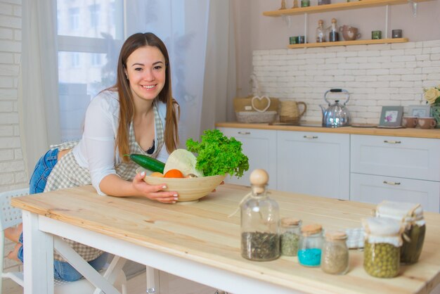 Eine junge schöne Frau bereitet in der Küche einen Salat mit verschiedenen Gemüsesorten zu. Das Konzept einer gesunden Ernährung und Lebensweise.