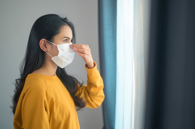 Eine junge schöne Frau, die eine schützende Gesichtsmaske trägt, die bereit ist, nach draußen zu gehen, Gesundheitswesen und covid-19 Konzept