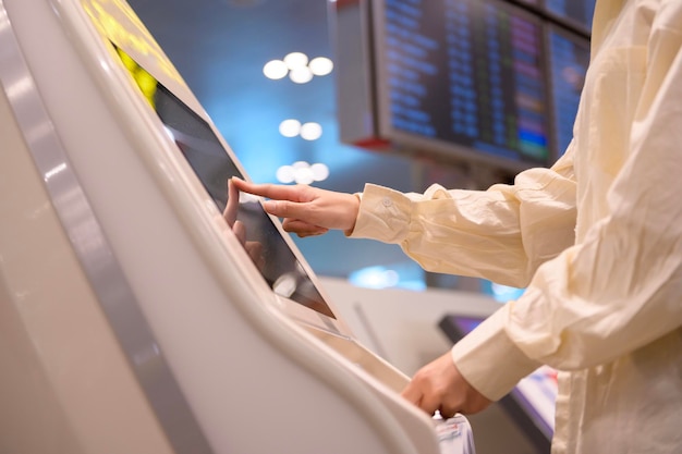 Eine junge schöne Frau, die mit Koffer am internationalen Flughafen eincheckt