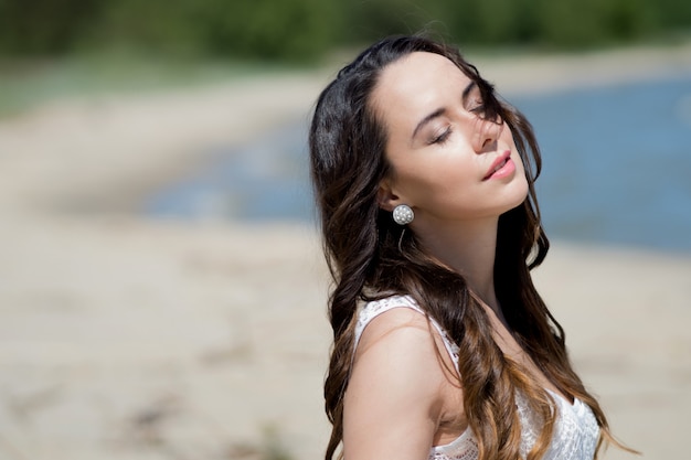 Eine junge schöne Frau in einem weißen Kleid geht am Strand spazieren