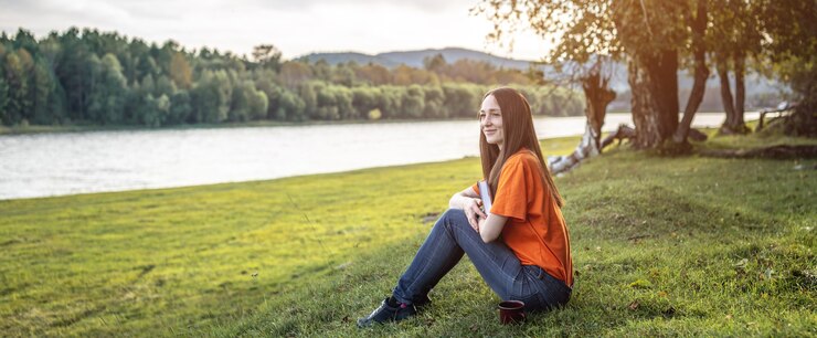 Foto eine junge schöne frau in hellen kleidern sitzt auf dem grünen gras und genießt das lesen eines buches in der natur. konzept eines angenehmen zeitvertreibs, ruhe, entspannung.