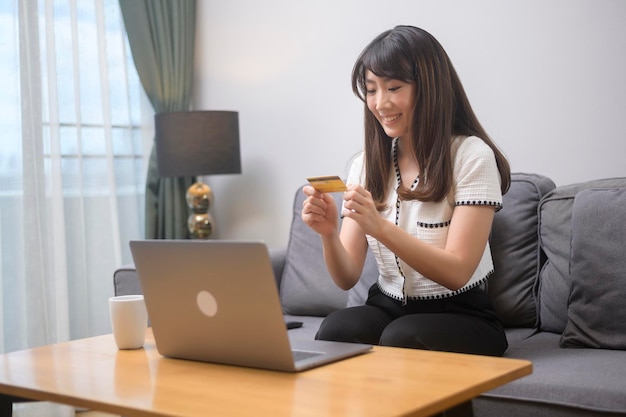 Eine junge schöne Frau verwendet Kreditkarte für Online-Shopping auf der Internet-Website zu Hause, E-Commerce-Konzept