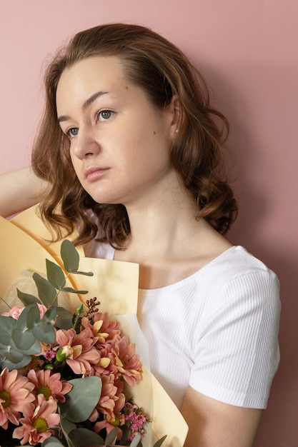 Eine junge selbstbewusste Frau hält einen großen Strauß Frühlingsblumen vor ihrem Frühlingskonzept