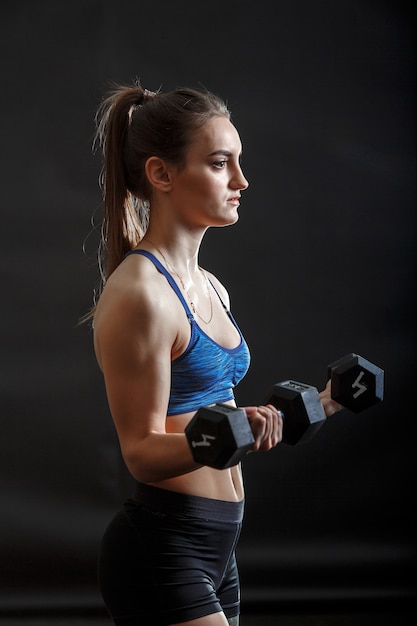 Foto eine junge sportdame mit pferdeschwanzfrisur in der eignungskleidung ausbildend mit dummköpfen