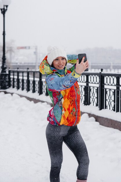 Eine junge sportliche Frau macht an einem frostigen und schneereichen Tag ein Selfie. Fitness, Erholung