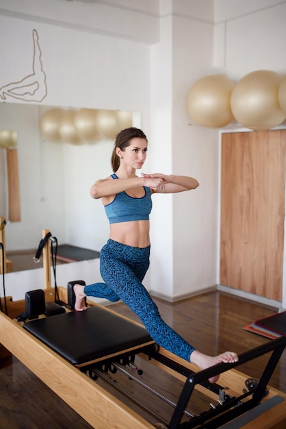 Eine junge sportliche Frau macht eine Übung auf einem Reformer Pilates Fitness