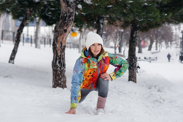 Eine junge sportliche Frau wärmt sich auf, bevor sie an einem frostigen Tag rennt. Fitness, Laufen