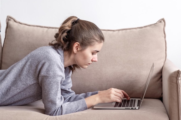 Eine junge Studentin arbeitet zu Hause an einem Laptop