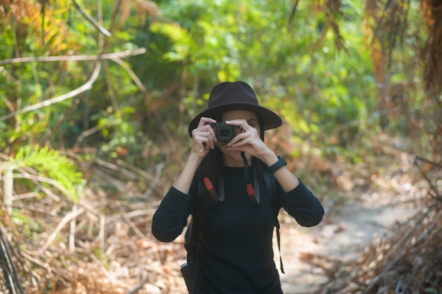 Eine junge Trekkerin, die Naturfotos mit Kamera im Wald macht, Urlaub und Reisekonzept.