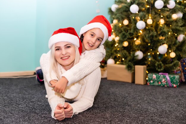 Eine junge und glückliche Mutter und Tochter in Weihnachtsmützen