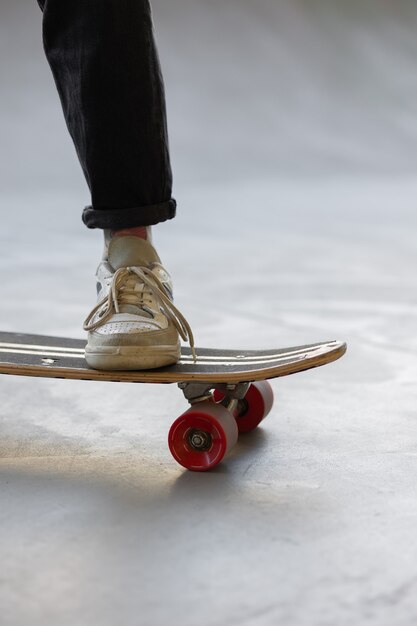 Foto eine junge und schöne skaterin, eine frau in einer orangefarbenen jacke, fährt ein skateboard auf einem skatepad