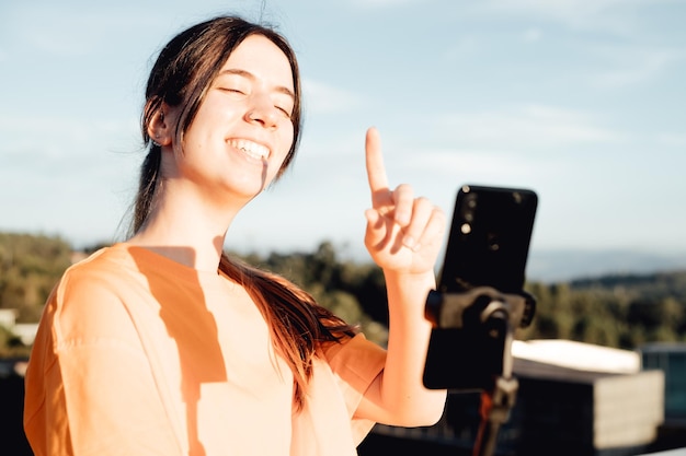 Eine junge Video-Bloggerin mit einem Lächeln im Gesicht nimmt Videos von sich selbst am Telefon auf, während sie in einem städtischen Raum sendet, während sie Sport-Influencer trainiert, die einen Clip von sich selbst mit dem Smartphone aufzeichnen
