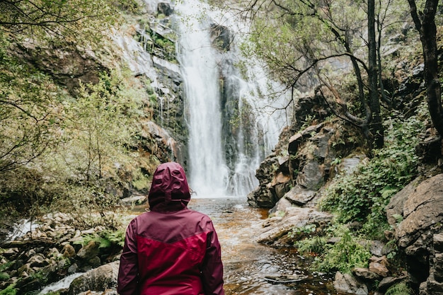 Eine junge Wanderin vor einem Wasserfall