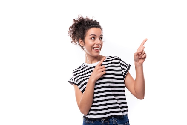 Eine junge weiße Frau mit einem lockigen Haarschnitt ist begeistert in einem gestreiften Sommer-T-Shirt gekleidet