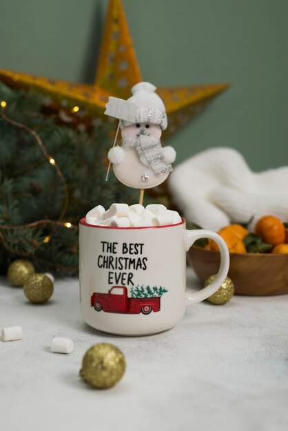 Eine Kaffeemütze mit Marchmellows und Schneemann auf weihnachtlichem Hintergrund