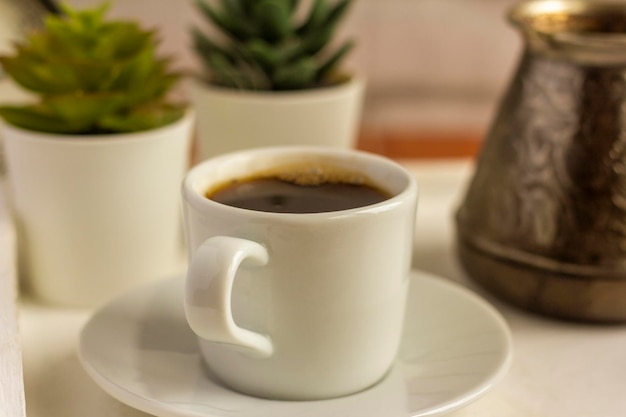Eine Kaffeetasse und ein Türke mit Kaffee auf einem Tablett. Das Konzept des guten Morgens.