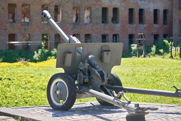 Eine Kanone aus dem Zweiten Weltkrieg vor dem Hintergrund eines zerstörten roten Backsteingebäudes