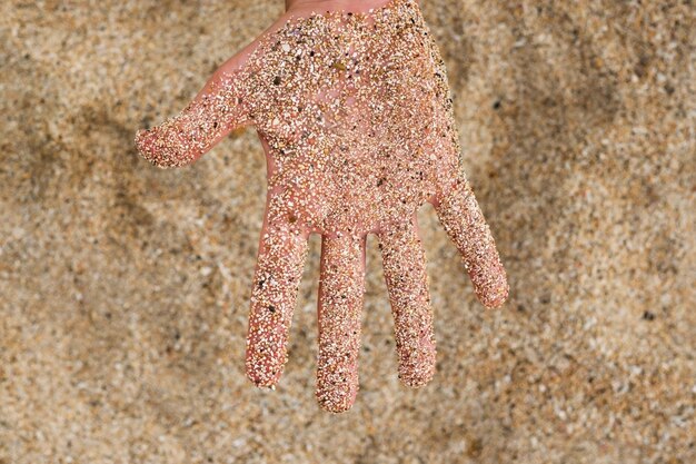 Eine kaukasische Hand im Sand am Strand