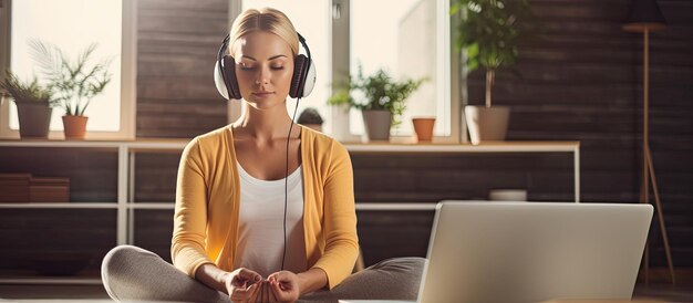 Foto eine kaukasische millennial-frau nutzt kopfhörer und einen laptop für eine online geführte meditation zu hause