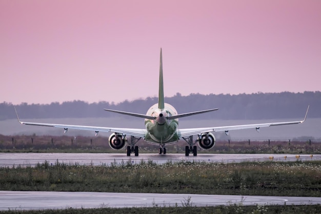 Eine Kehrtwende eines Passagierflugzeugs auf der Landebahn im Abendlicht. Rückansicht