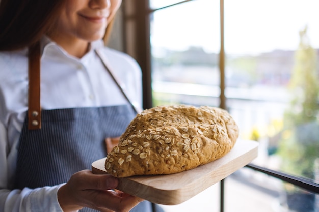 Eine Kellnerin, die einen Laib Vollkornbrot hält und serviert