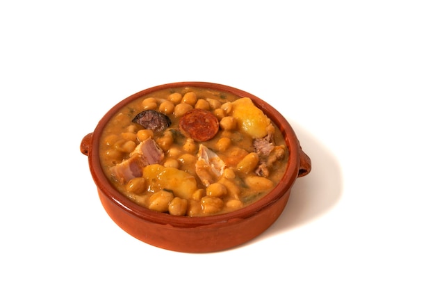 Eine Kichererbsensuppe in einer Tonschüssel, isoliert auf weißem Hintergrund. Spanisches Food-Konzept