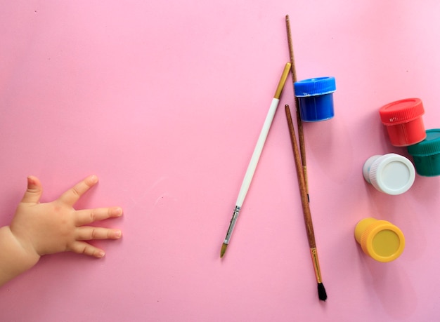 Eine Kinderhand hält Pinsel und malt Draufsicht mit Platz für Text, der sich auf die Schule vorbereitet