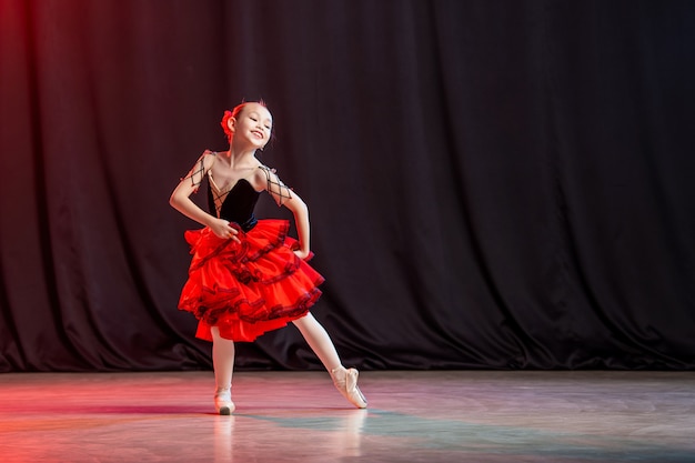 Eine kleine Ballerina tanzt auf der Bühne im Tutu auf Spitzenschuhen mit Castanedas, der klassischen Variante von Kitri.