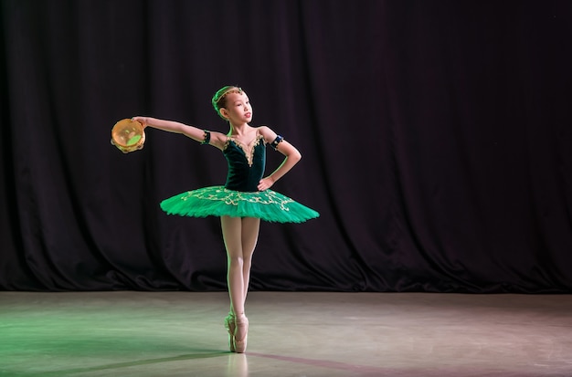 Eine kleine Ballerina tanzt auf der Bühne in einem Tutu auf Spitzenschuhen mit Tamburin, einer klassischen Variation von Esmeralda.