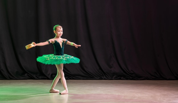 Eine kleine Ballerina tanzt auf der Bühne in einem Tutu auf Spitzenschuhen mit Tamburin, einer klassischen Variation von Esmeralda.