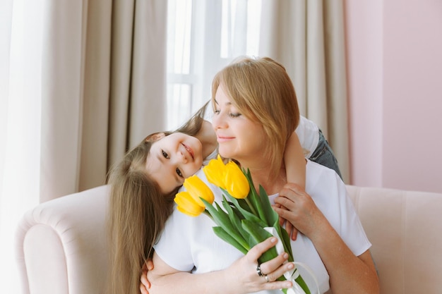 Eine kleine Enkelin gibt ihrer Großmutter einen Strauß Tulpen Eine glückliche Familie Das Konzept der Dankbarkeit liebt das Wohlbefinden
