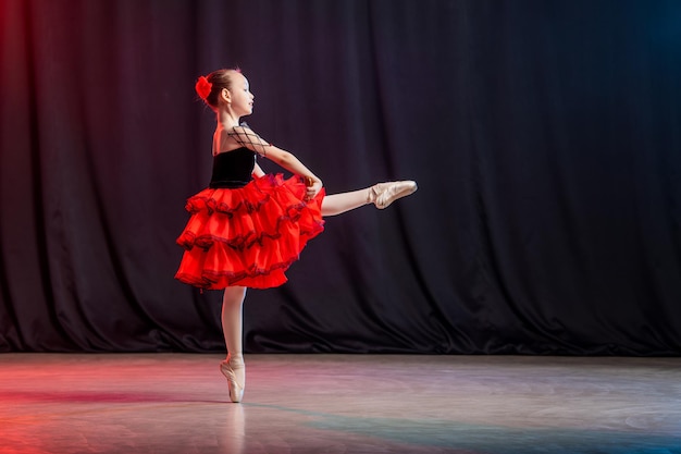 Eine kleine Mädchen-Ballerina tanzt auf der Bühne in einem Tutu auf Spitzenschuhen mit Castanedas, der klassischen Variante von Kitri.