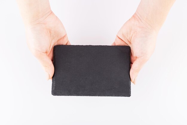 eine kleine schwarze Schieferplatte wird von weiblichen Händen präsentiert