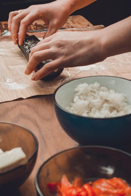 Eine Köchin bereitet in der Küche Sushi zu und wickelt einen Brief an die Nori in die Rolle