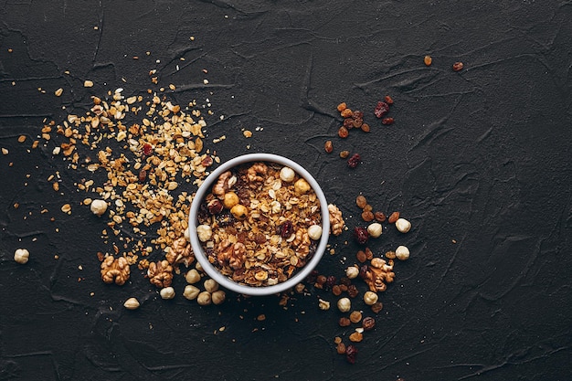 Eine köstliche und knusprige Haferflocken-Granola mit Honig, Nüssen, getrockneten Früchten und Körnern wird aus der Praml-Packung in einen Teller gegossen.