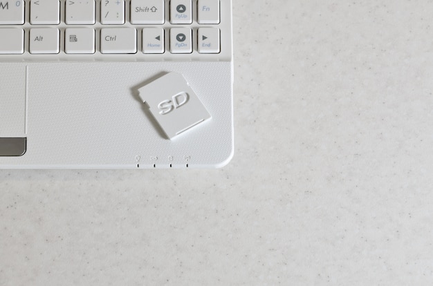 Eine kompakte SD-Speicherkarte liegt auf einem weißen Netbook. Das