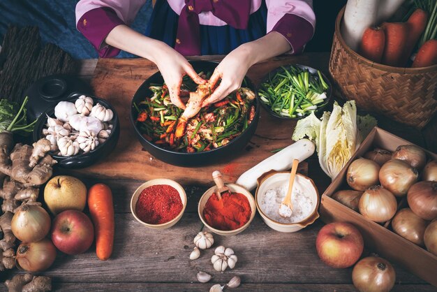 Foto eine koreanische frau trägt einen traditionellen hanbok und macht kimchi, ein fermentiertes essen.