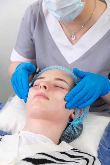 Eine Kosmetikerin behandelt die Haut des Patienten manuell mit einem feuchtigkeitsspendenden und straffenden Gel