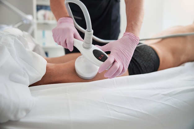 Foto eine kosmetikerin, die handschuhe trägt und eine nicht-invasive ultraschall-hautbehandlung für einen klinikbesucher durchführt