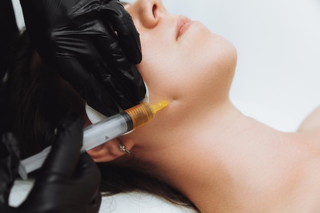 Foto eine kosmetikerin führt plasmolifting auf dem gesicht einer schönen frau in einem schönheitssalon durch das konzept der kosmetologie