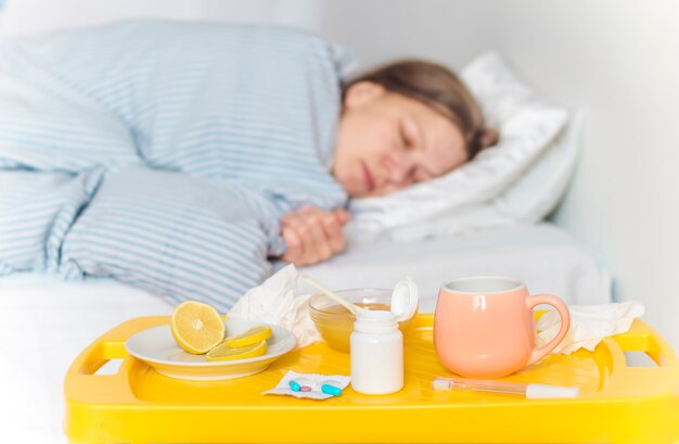 Eine kranke Frau mit Erkältung oder Grippe liegt mit Fieber im Bett.