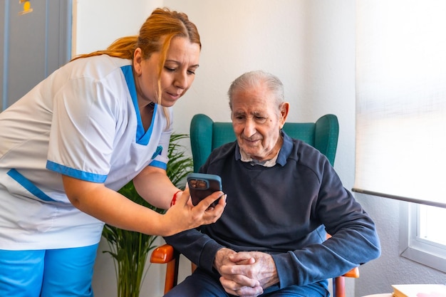 Eine Krankenschwester hilft einem älteren Mann in der Geriatrie mit Technologie