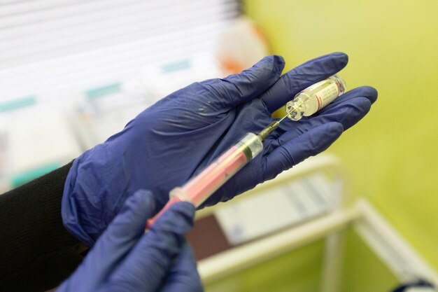 Foto eine krankenschwester in blauen handschuhen zieht medizin in eine spritze für eine injektion behandlung im krankenhaus