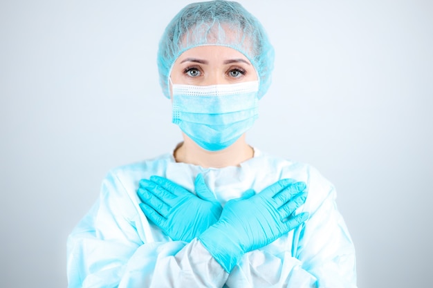Eine Krankenschwester in einem medizinischen Kleid, einer Maske und Schutzhandschuhen drückte ihre Hände an ihre Brust.